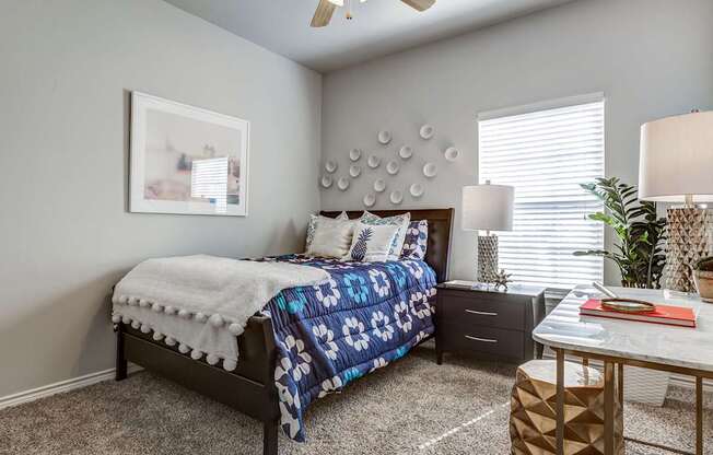 A bedroom with a bed, nightstand, and a ceiling fan.