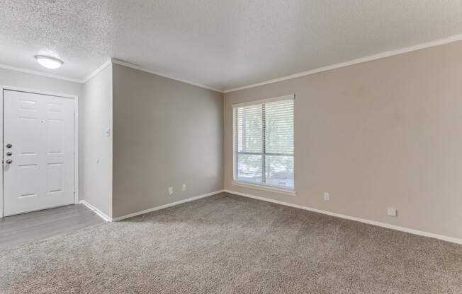 an empty bedroom with a window and a door