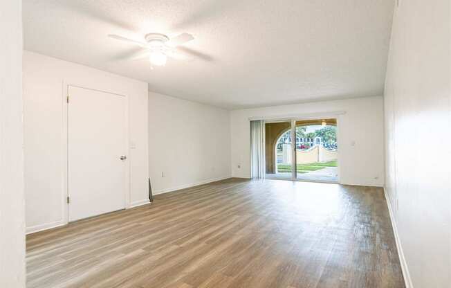 an empty living room with wood flooring and a door to a patio