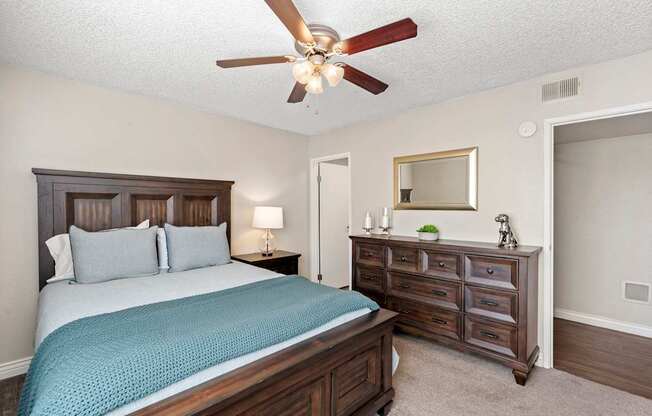 A bedroom with a bed, nightstand, and a ceiling fan.