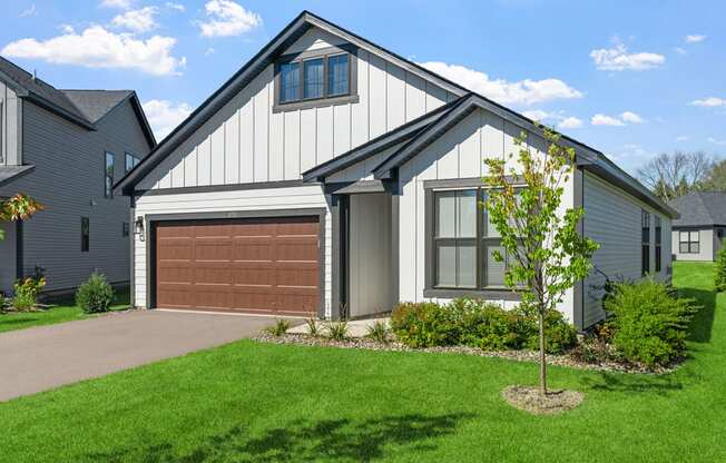 a home with a brown garage door in front of a green lawn