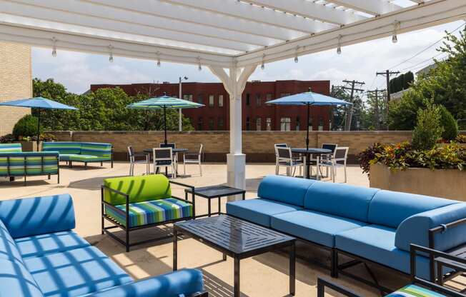 a patio with blue couches and green and blue chairs and umbrellas