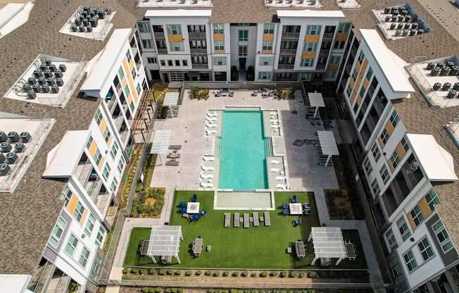 an aerial view of a building with a pool and lawn