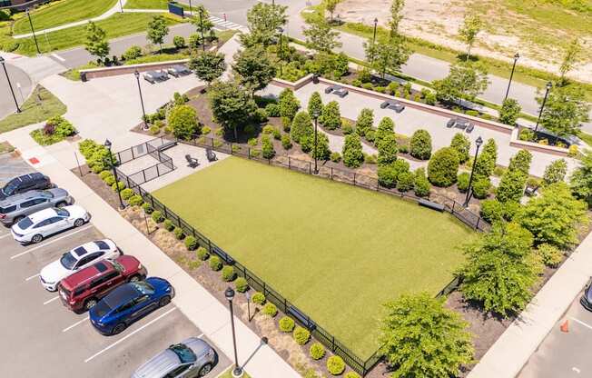 A parking lot with cars and a green field.