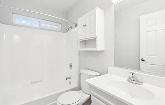 A white bathroom with a toilet, sink, and medicine cabinet.