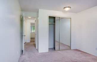 an empty bedroom with mirrored closet doors and a carpeted floor