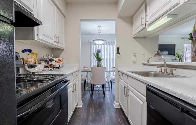 A kitchen with black appliances and white cabinets. at 2400 Briarwest Apartments, Houston, TX