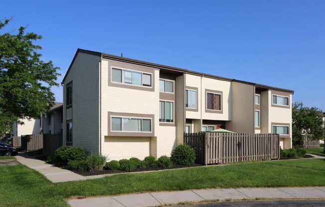 an apartment building with a wooden fence and a blue sky in the background