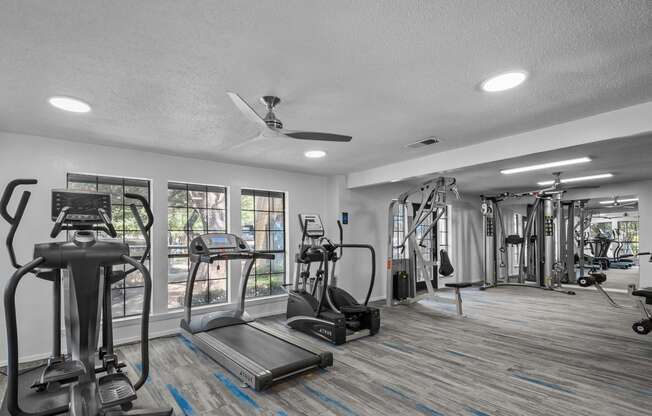 a gym with weights and cardio machines and a ceiling fan