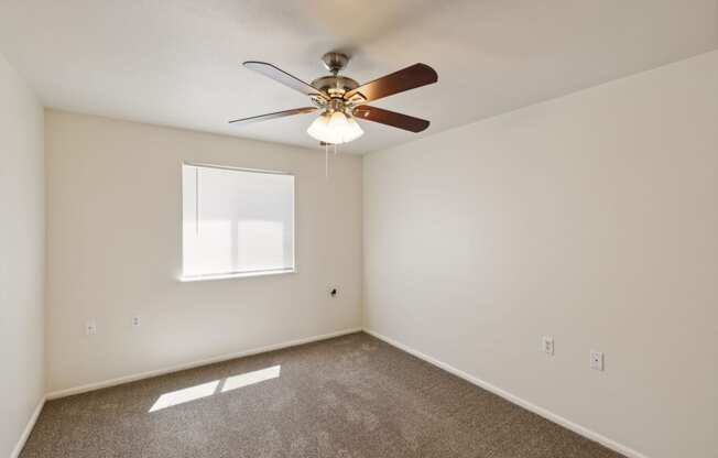 an empty room with a ceiling fan and a window