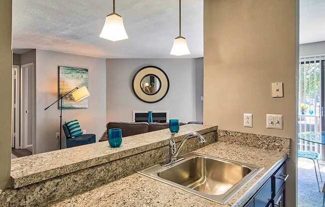 A kitchen with a granite countertop and a round mirror above the sink.