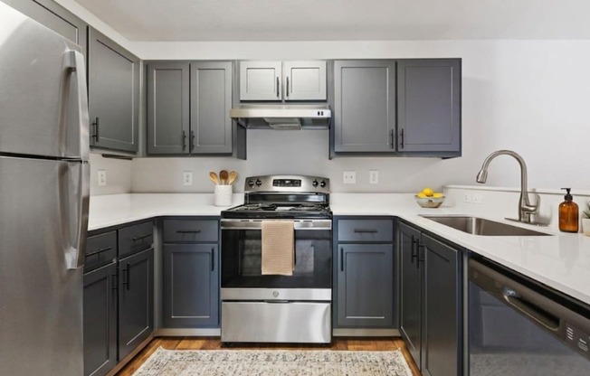 A modern kitchen with dark grey cabinets and stainless steel appliances.