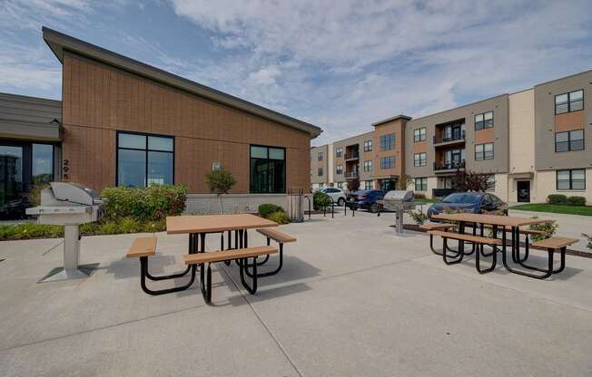 an outside patio area with picnic tables in front of an apartment building at Statesman Apartments, Franklin, Wisconsin