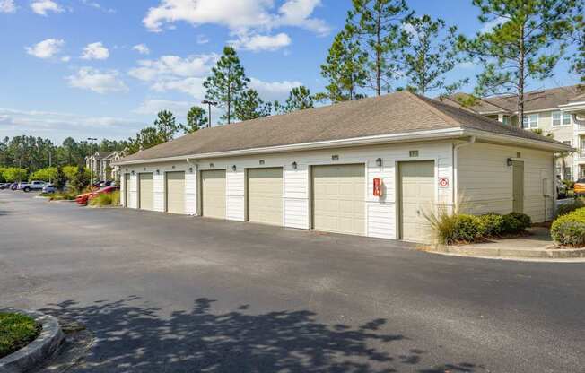A building with a grey roof and white garage doors is surrounded by a parking lot.