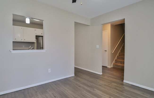 the living room and kitchen of an empty apartment with wood flooring