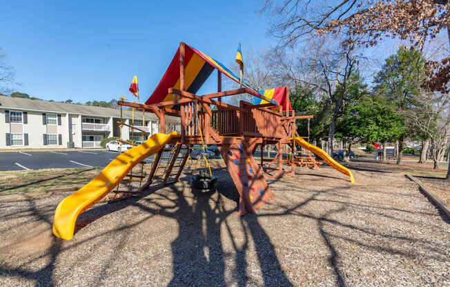 A playground with a yellow slide and a red and yellow structure at Madison Woods apartments in Greensboro, NC.