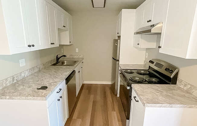 A kitchen with white cabinets and a marble countertop.