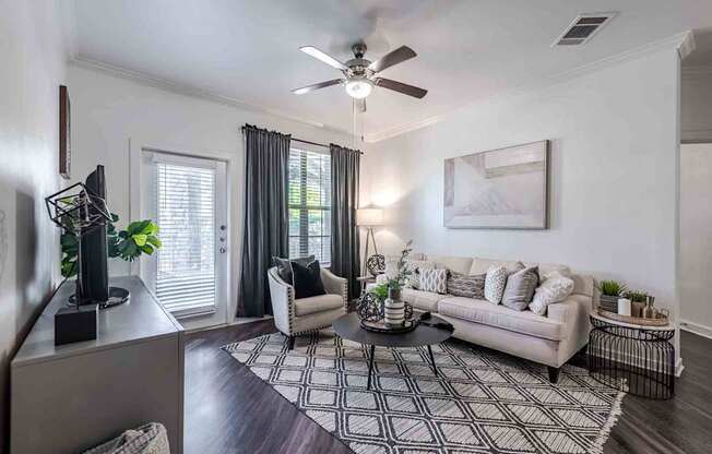 A living room with a white couch, a coffee table, and a ceiling fan.