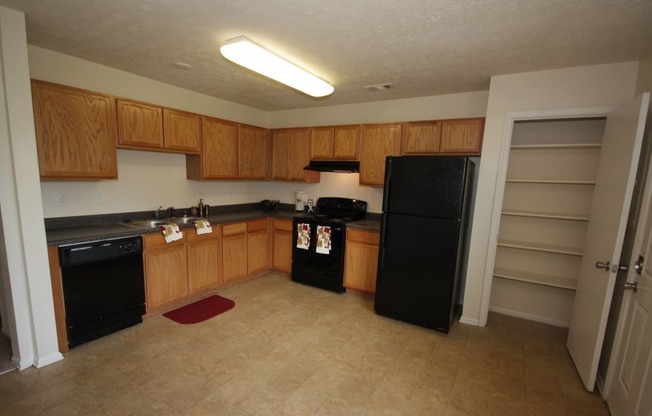 Kitchen with wood cabinets and stainless steel sink and black appliances