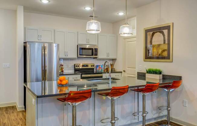 A modern kitchen with a bar area and stools.