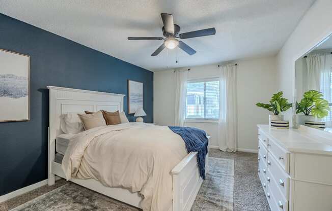 the master bedroom has a large bed and a ceiling fan