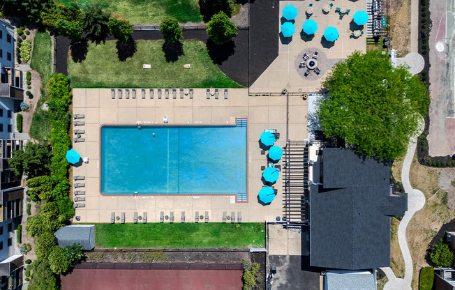 a birds eye view of the pool of a building with umbrellas