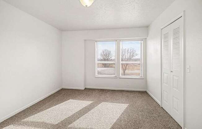 A room with a carpeted floor and a window showing a snowy landscape outside.