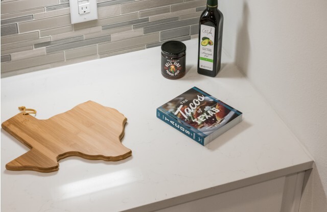 Detail of kitchen counter with Texas shaped cutting board and recipe book at Tinsley on the Park | Apartments in Houston