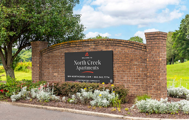 a brick wall with a sign that says north creek apartments