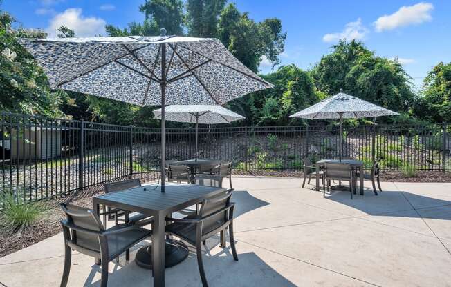 a patio with tables and umbrellas and a fence