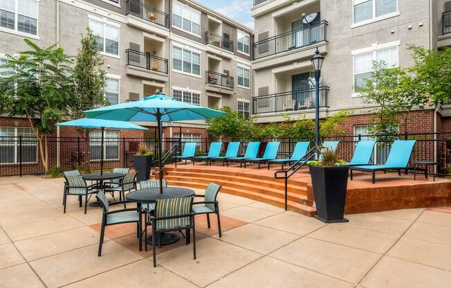 a patio with tables and chairs and umbrellas at an apartment building