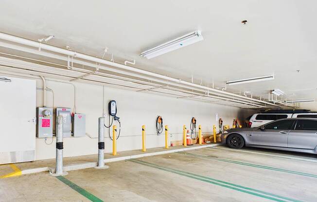 A parking garage with a car parked and multiple charging stations.