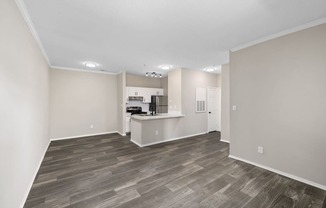 an empty living room and kitchen with wood flooring