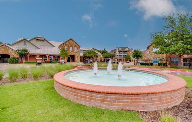 a fountain in the middle of a park in front of a house