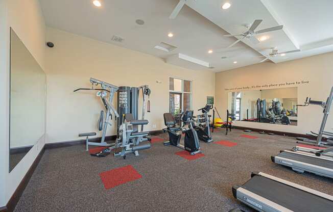 a gym with cardio equipment and weights in a building with white walls