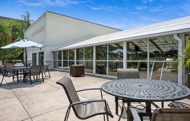 a patio with tables and chairs and a building in the background