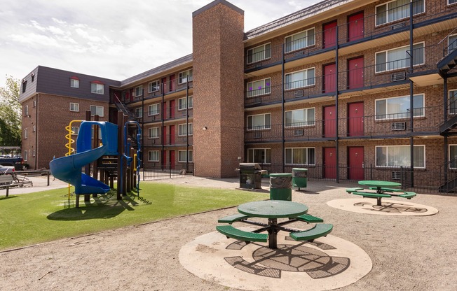 a playground in the courtyard of an apartment building with a blue slide