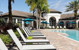 a pool with lounge chairs and a building in the background