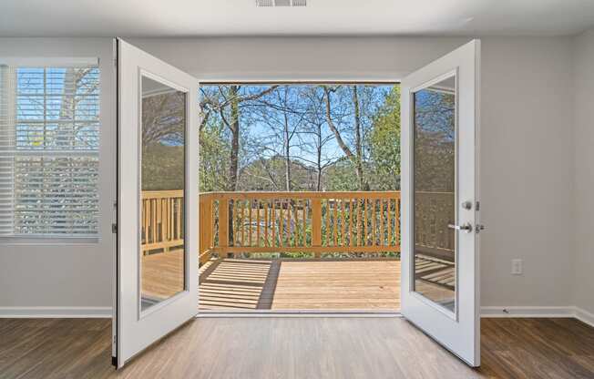 an open door leading to a balcony with a view of the woods