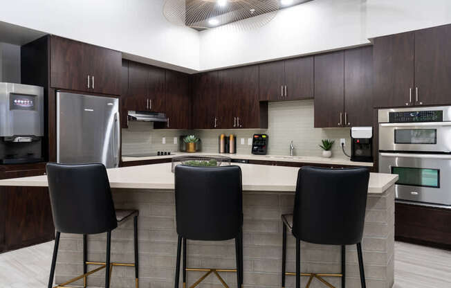 A kitchen with a bar area and three black chairs.