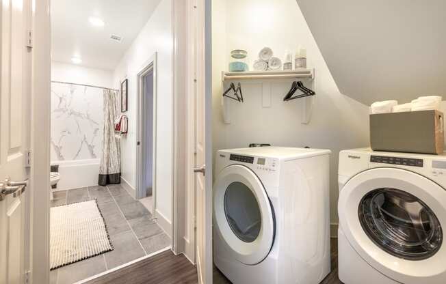 Inside of walk-in closet facing in-unit washer and dryer facing into the bathroom