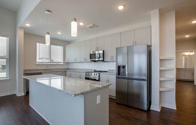 A modern kitchen with a granite countertop and stainless steel appliances.