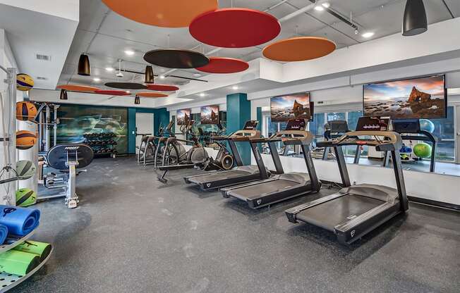 a gym with treadmills and other exercise equipment in a building with colorful ceilings