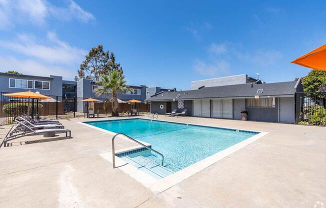 A swimming pool surrounded by a concrete patio and a metal fence.