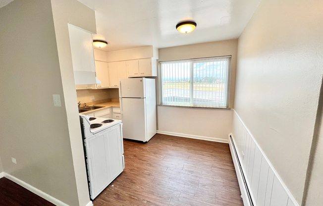 Bright and modern kitchen with sleek white cabinetry, cozy dining area, and large window offering scenic views.