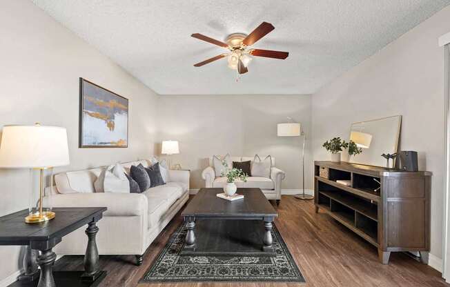 A living room with a white couch, a black coffee table, and a ceiling fan.