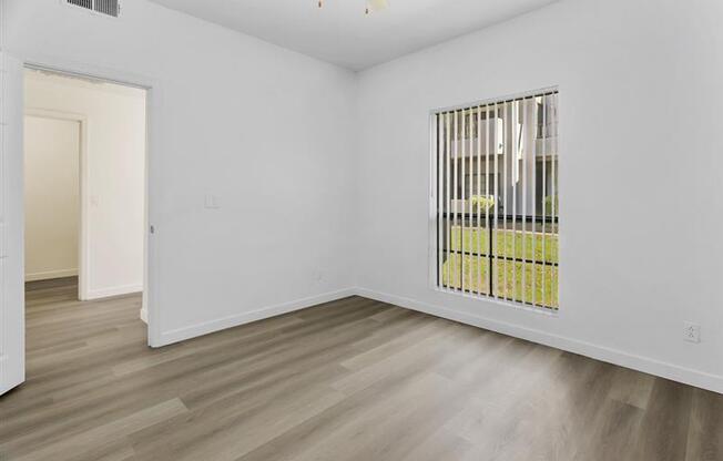 A room with a window and a wooden floor.