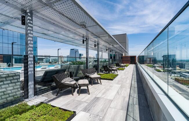 Rooftop promenade with shaded seating, planters, and glass railings offering relaxed lounge areas and expansive city views.