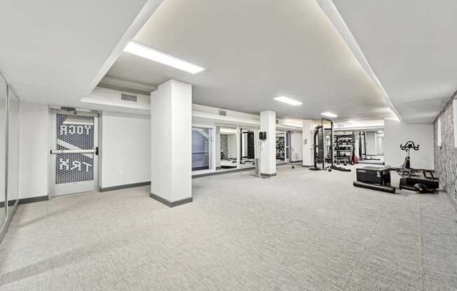 A spacious gym with a variety of equipment and a white color scheme.