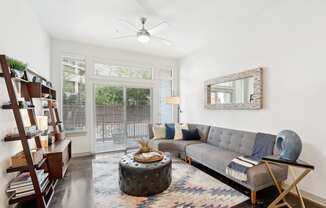 Model living room with a gray couch and a large doorway to patio at Harlow River Oaks in Houston, TX